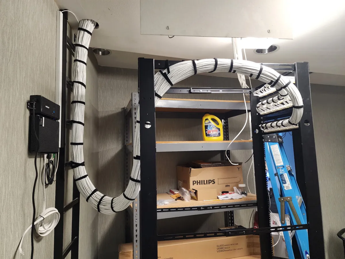 Cable service loop dressed on two-post rack in MDF closet — velcro-tied bundles with patch panels