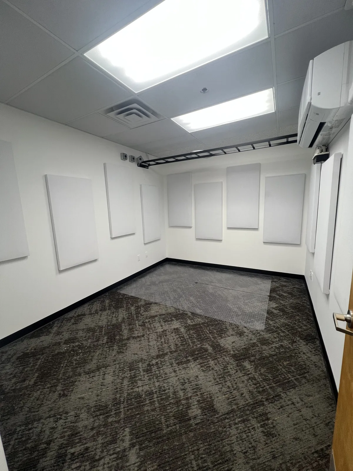 Room with acoustic wall panels, mini-split AC, and overhead cable tray — mid-construction