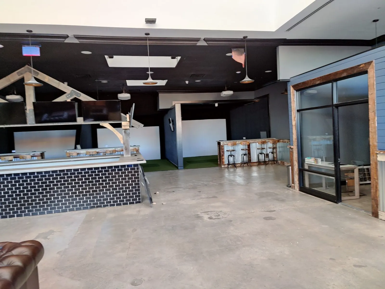 Entertainment venue bar with mounted TVs, tile front, and distributed audio
