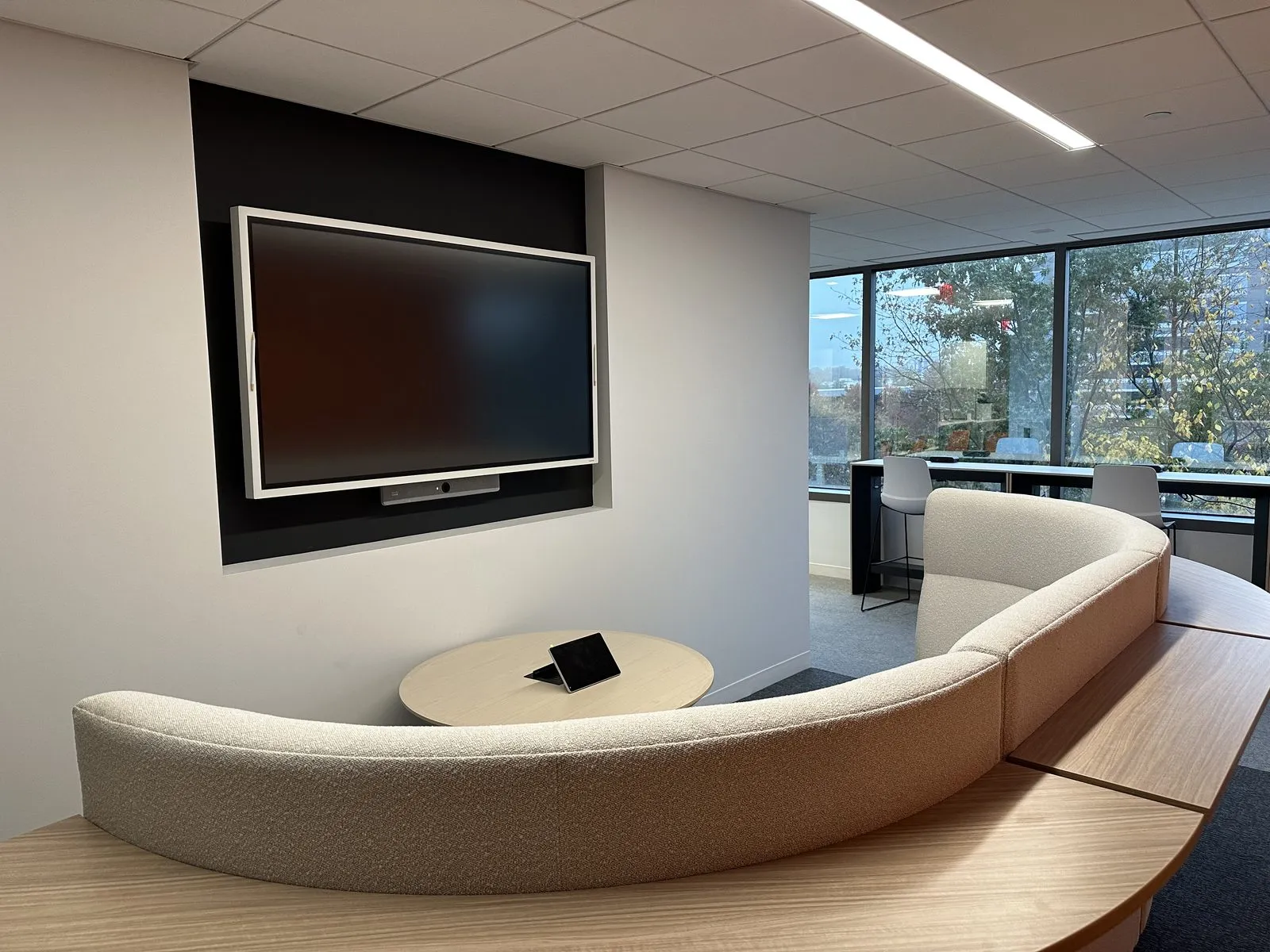 Huddle room with curved sofa seating and integrated AV — wide-angle view